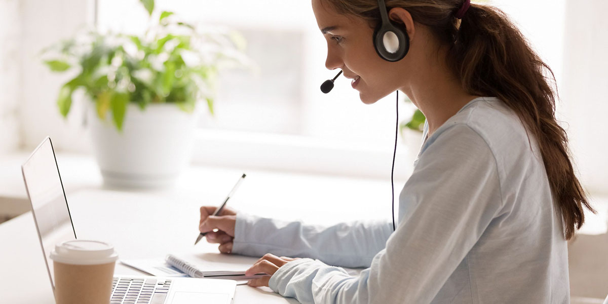  woman wearing headset with microphone, looking at laptop screen