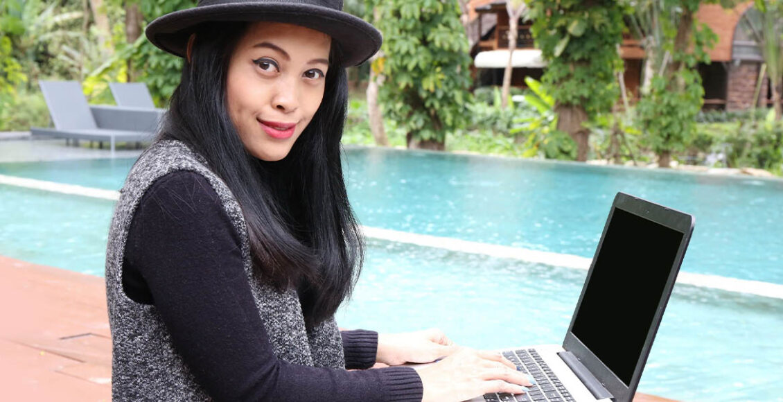 woman working with laptop beside a pool