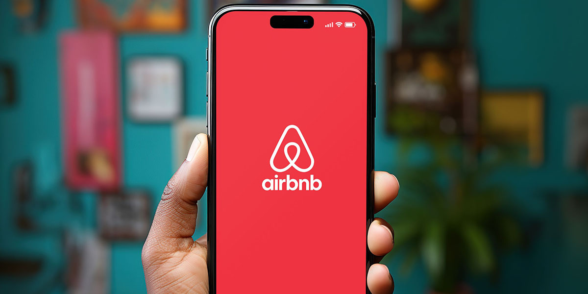 hand holding a smartphone iPhone with Airbnb app on the screen 