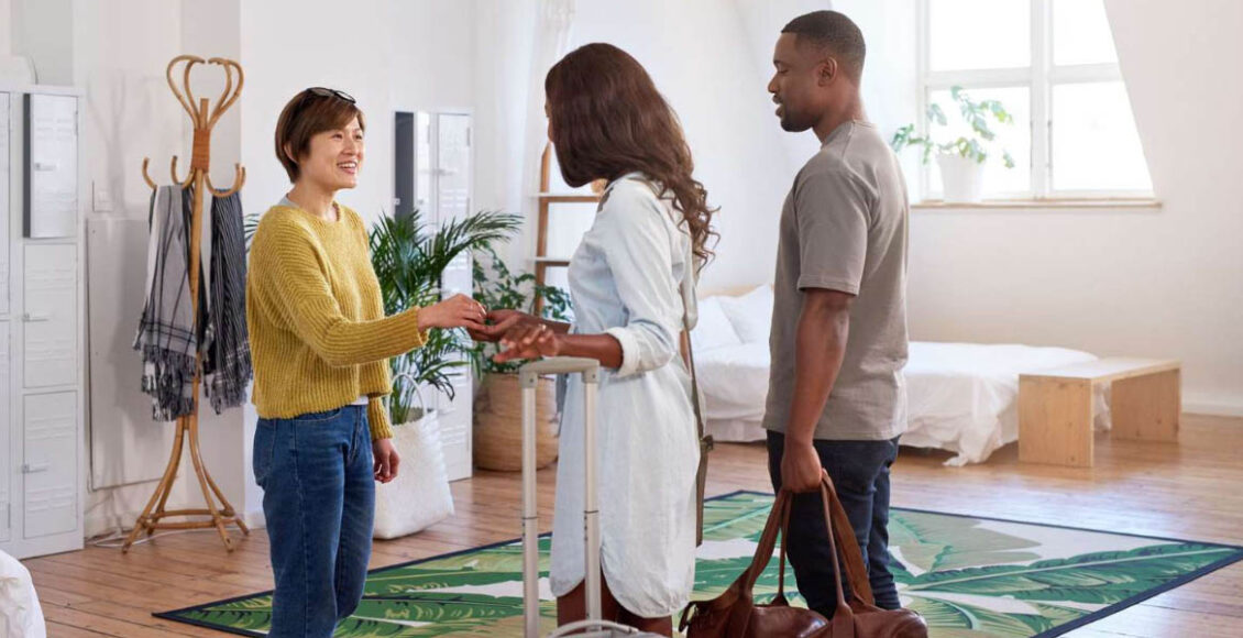 an airbnb host shaking hand with two guests