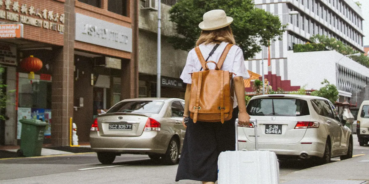 View of a Woan on City Street with a Luggage